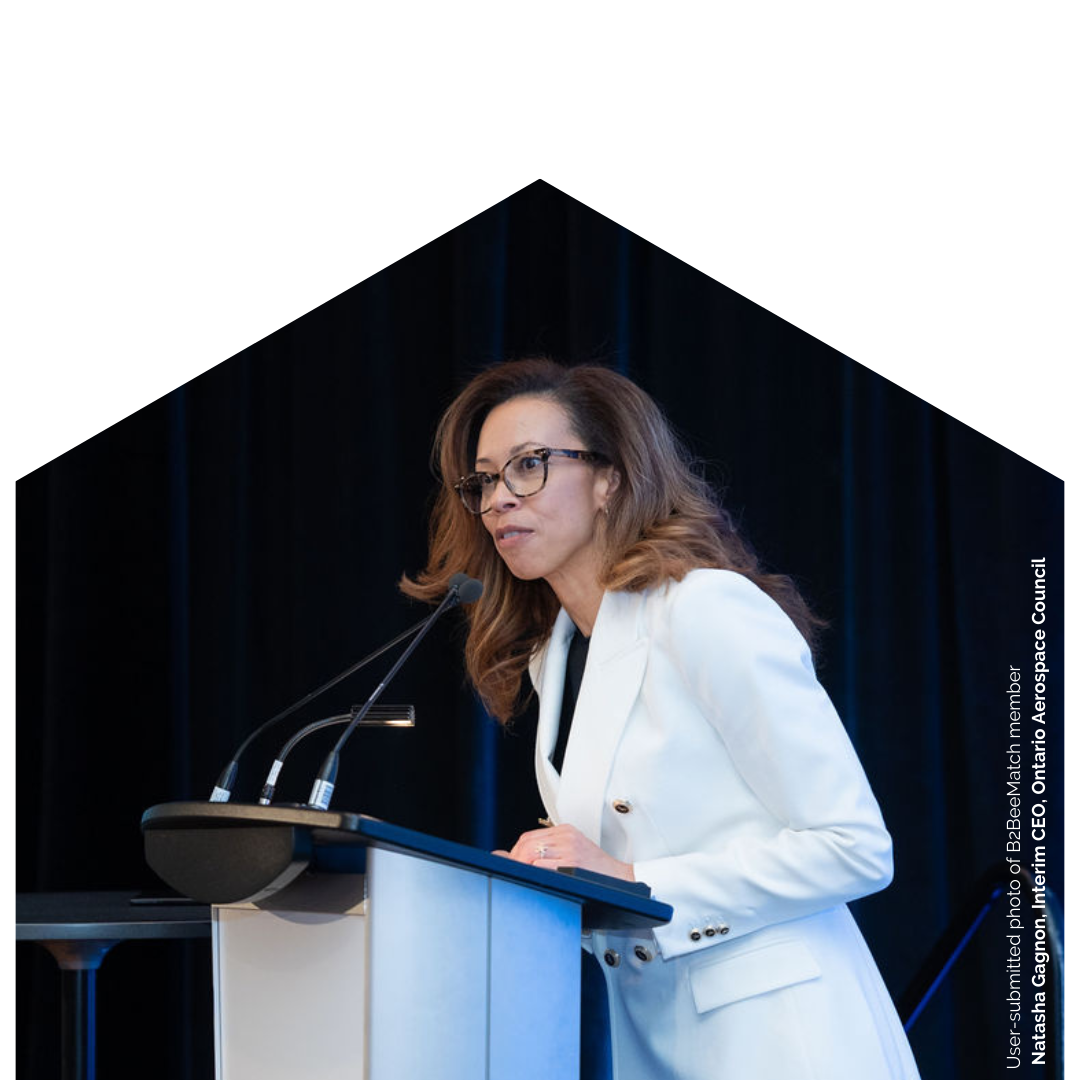 Natasha Gagnon, B2BeeMatch partner, addresses a B2B business networking event for the aerospace sector wearing white.